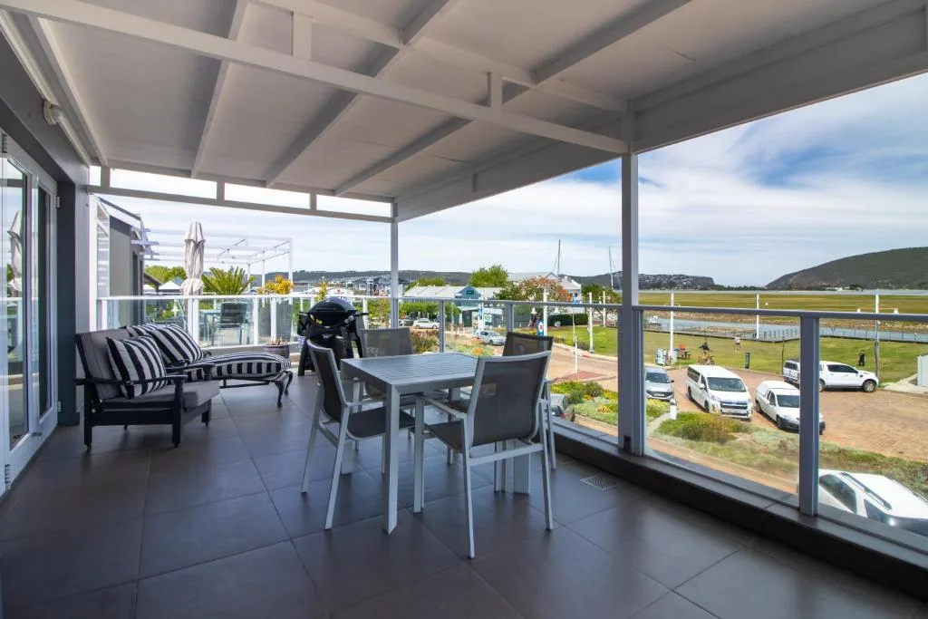 Covered outdoor deck with dining table, seating, and scenic harbor views