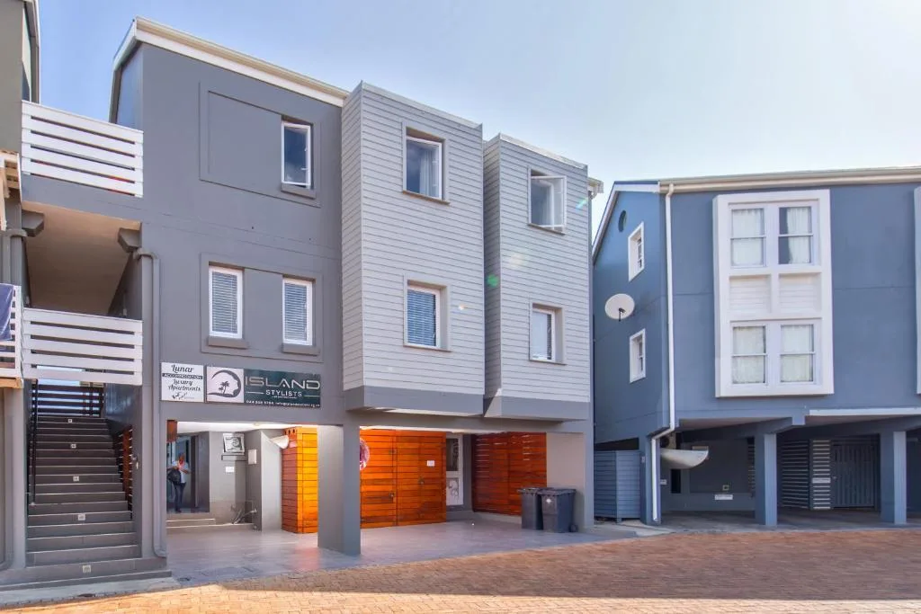 Modern apartment building facade with gray cladding and orange garage doors