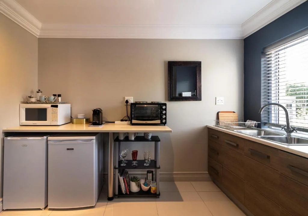 Modern kitchenette with stainless steel sink, compact appliances and wooden cabinetry