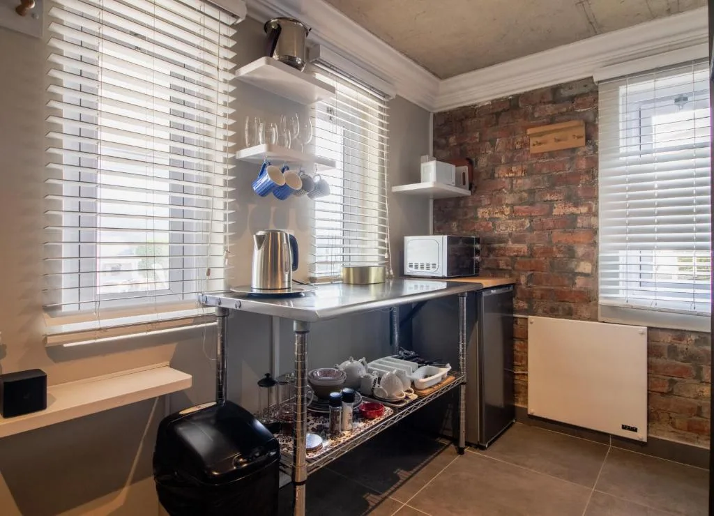 Modern kitchenette with stainless steel kettle, microwave, and open shelving