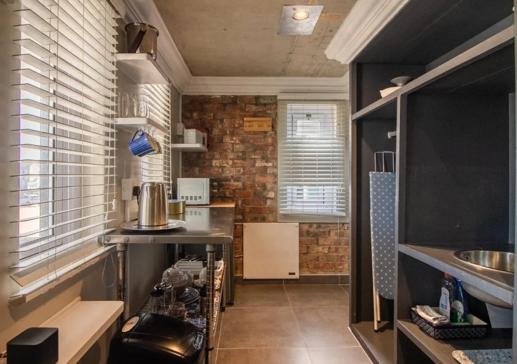 Modern kitchen with stainless steel appliances, brick accent wall, and open shelving