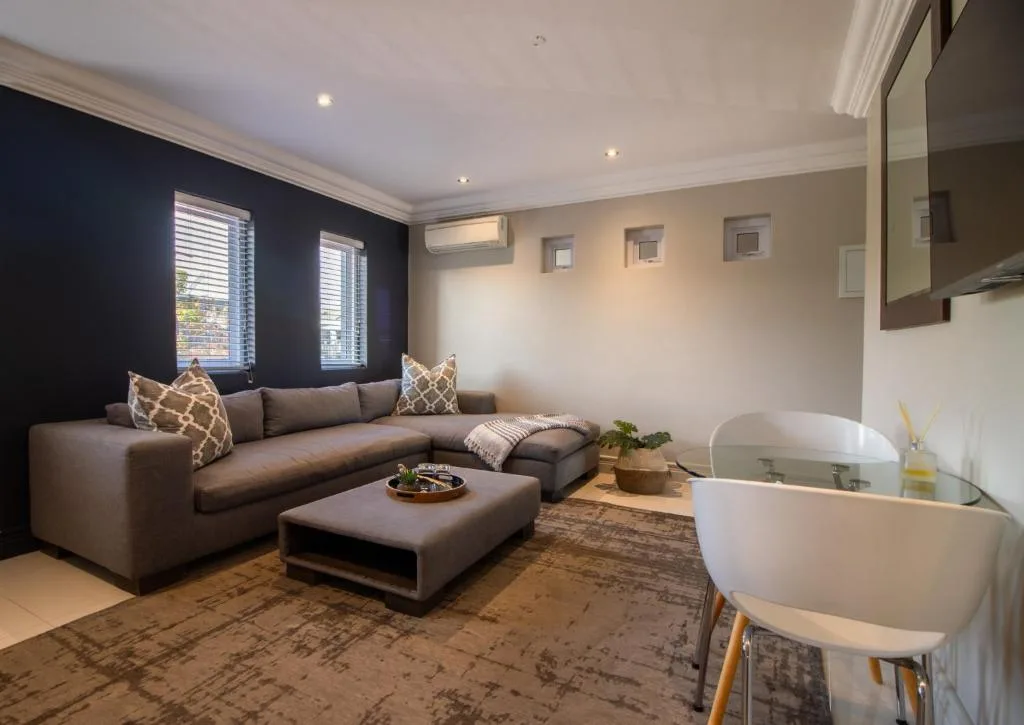 Modern living room with gray sectional sofa, dark accent wall, and windows