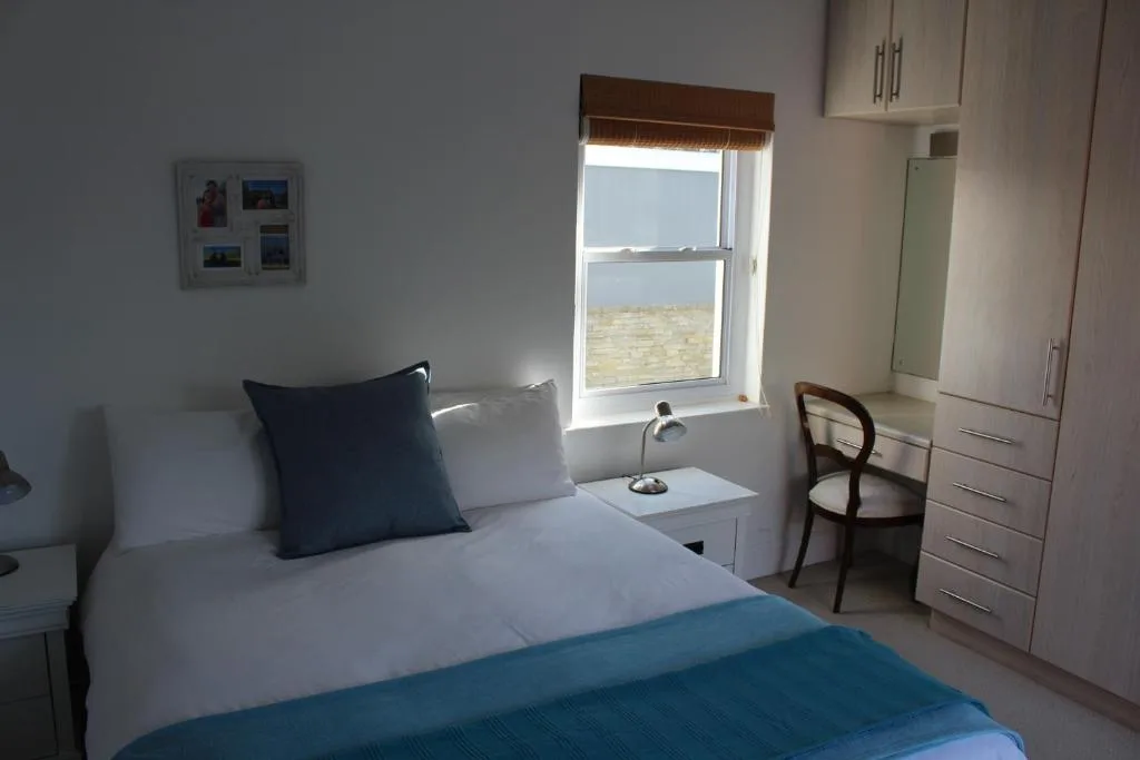 Bright bedroom with double bed, desk, storage, and large window overlooking water
