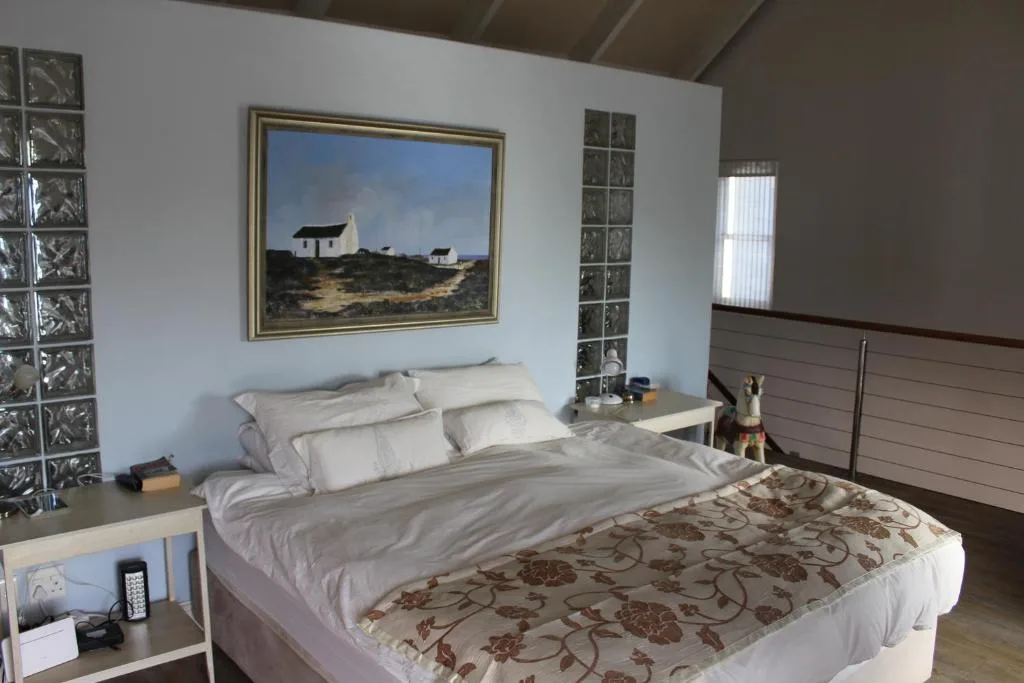 Spacious bedroom with queen bed, neutral bedding, framed landscape artwork above headboard