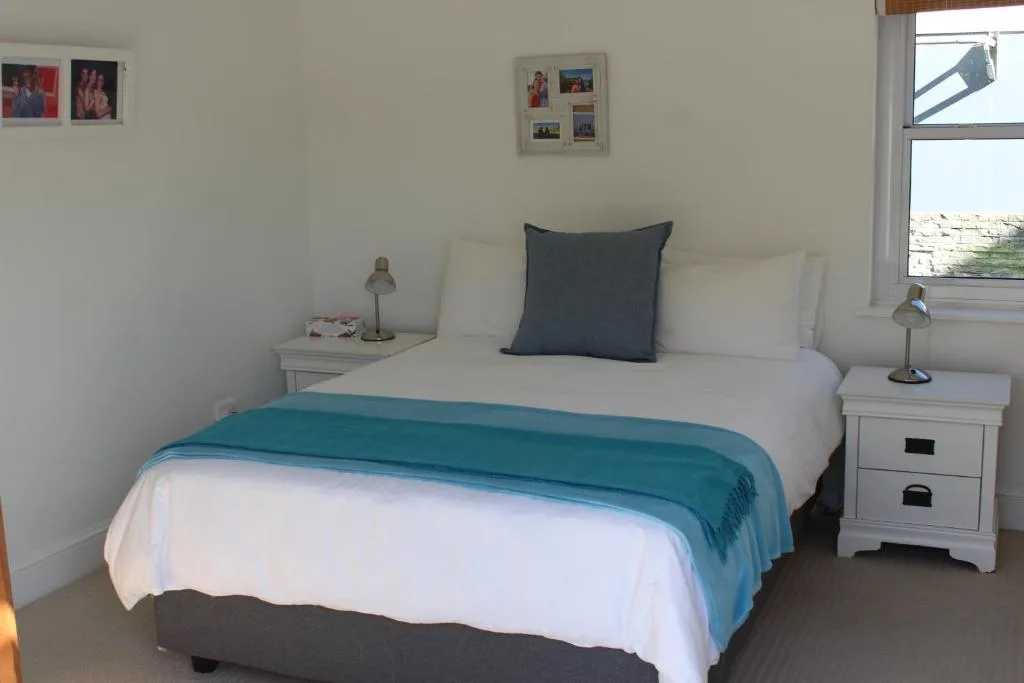 Bright bedroom with queen bed, turquoise throw, white bedside tables with lamps