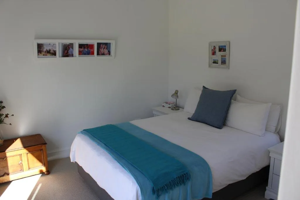 Bright bedroom with queen bed, teal throw, and bedside lamp