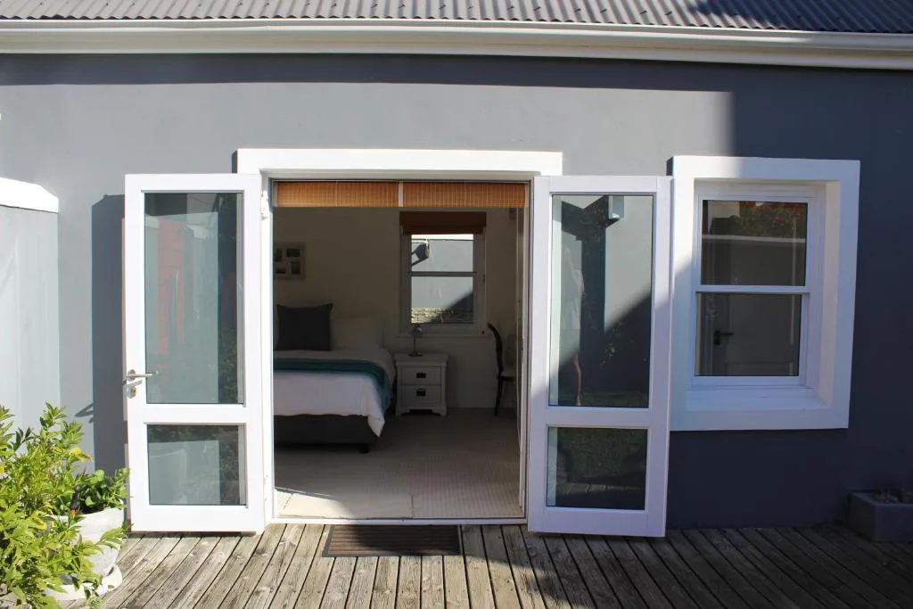 Bright bedroom with bed visible through open glass doors and deck access