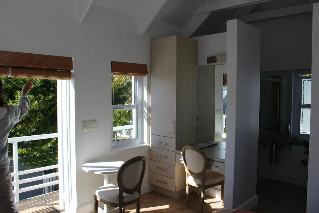 Bright bedroom with built-in wardrobe, two chairs, and garden views through windows