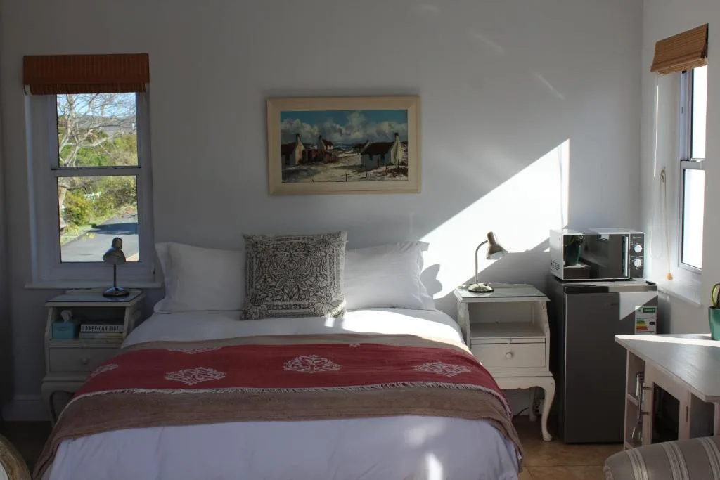Bright bedroom with bed, nightstands, and water view through windows