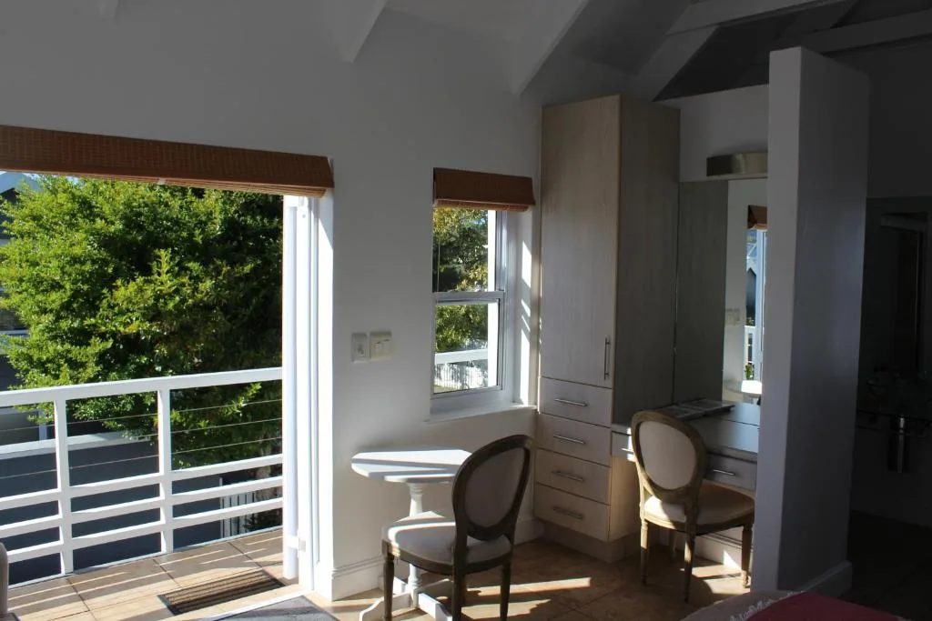 Bright bedroom with deck access, twin chairs, and lush garden views outside