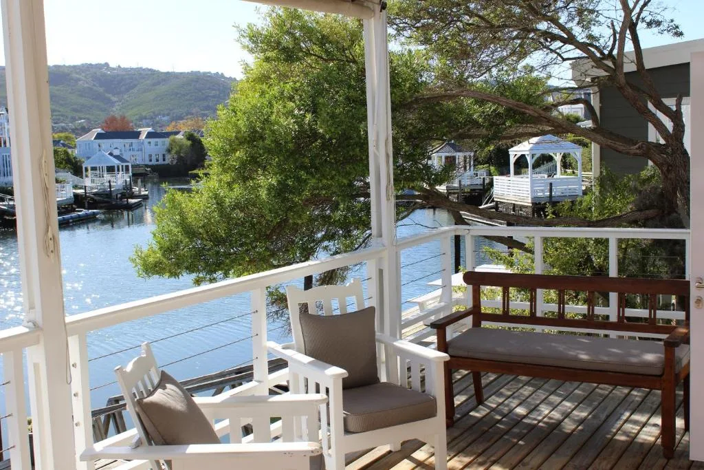 Wooden deck with white railings overlooking calm lagoon water and lush vegetation