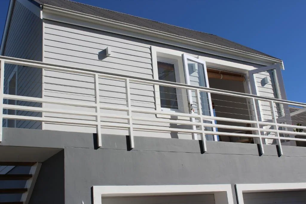 Modern white and grey residential building with metal railings on deck
