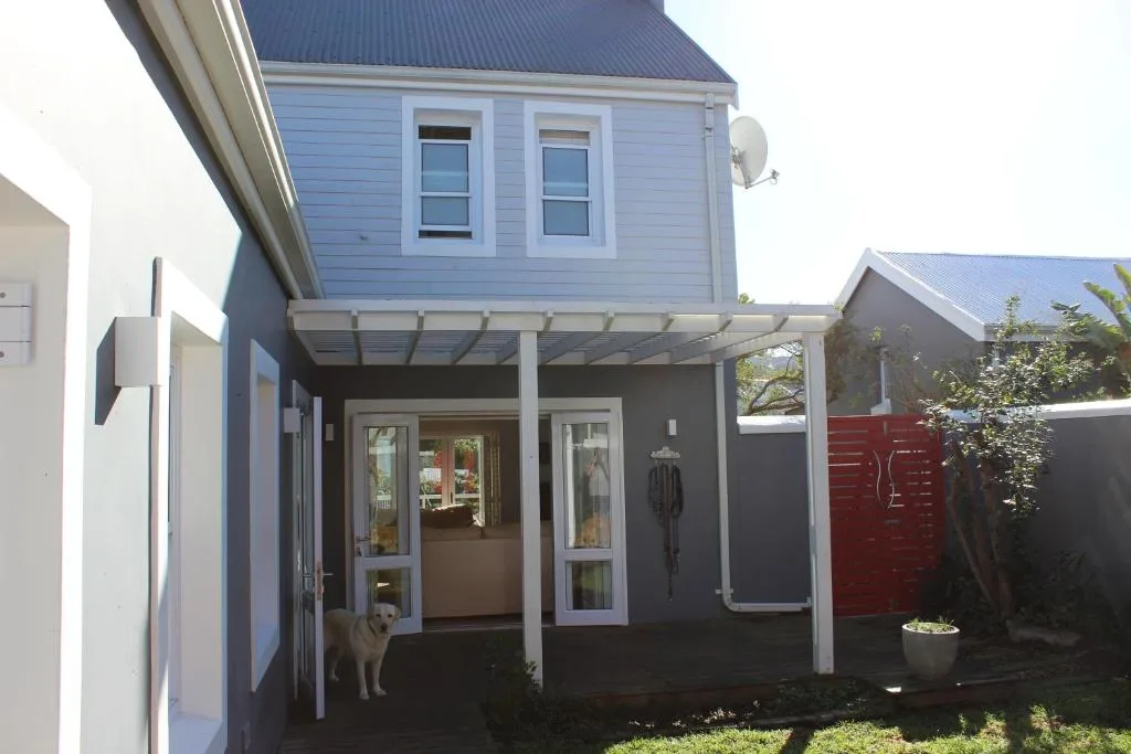 Modern blue and white house with covered entrance porch and garden gate