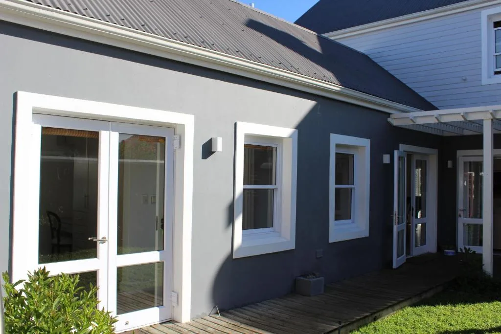 Modern home exterior with white-framed glass doors and dark blue walls