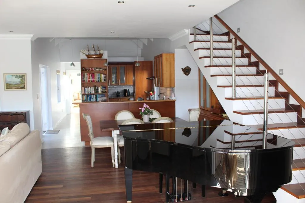 Open-plan living area with grand piano, dining table, and staircase