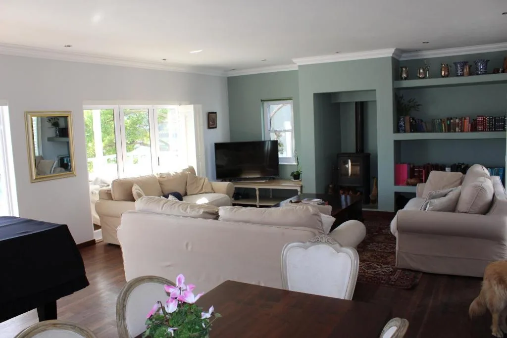 Spacious living room with cream sofas, TV, fireplace, and garden views