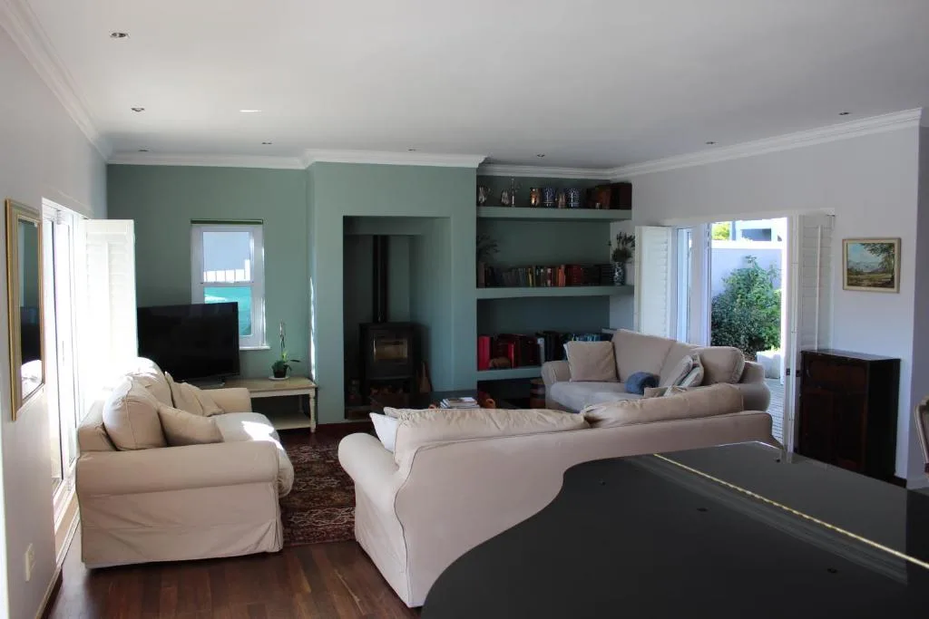 Spacious living room with cream sofas, green accent walls, and built-in shelving