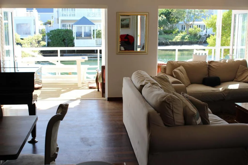 Spacious lounge with tan sofas overlooking waterfront deck and lagoon views