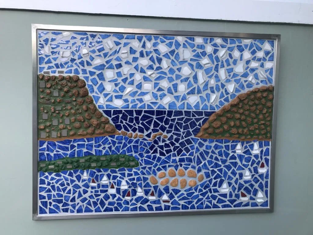 Framed mosaic artwork depicting landscape with blue tiles and natural elements