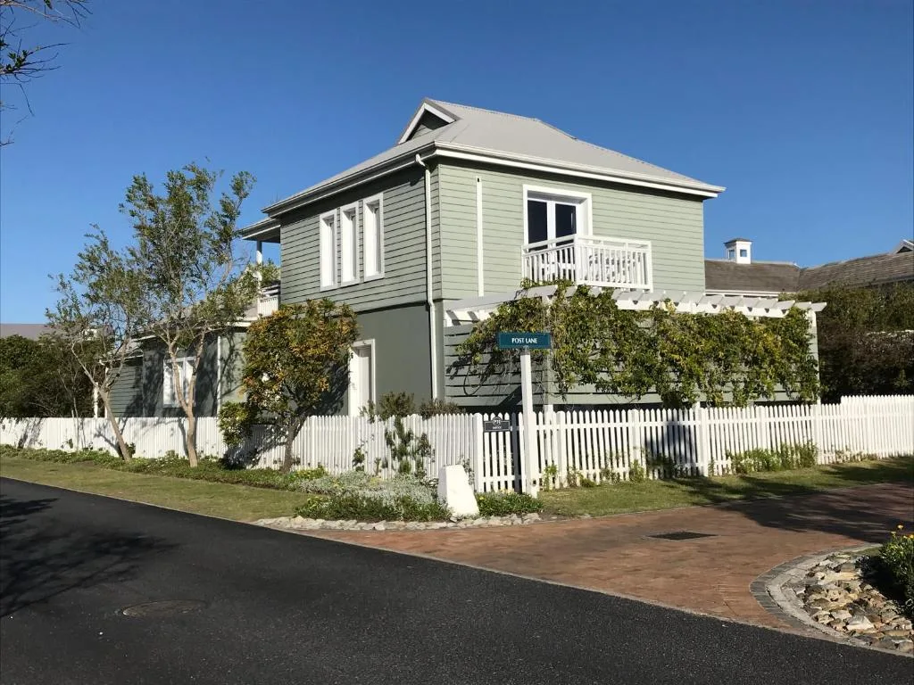 Charming two-story cottage with white picket fence and manicured gardens