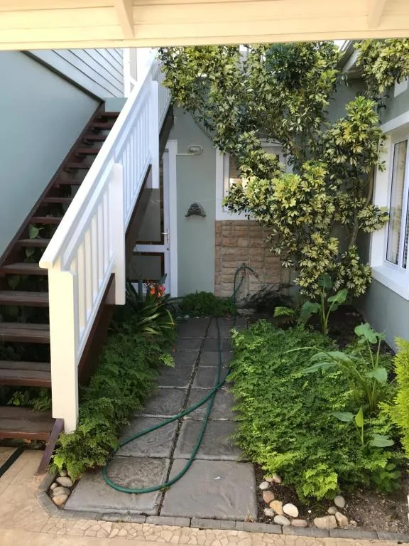 Sheltered entrance pathway with wooden stairs and lush green climbing plants