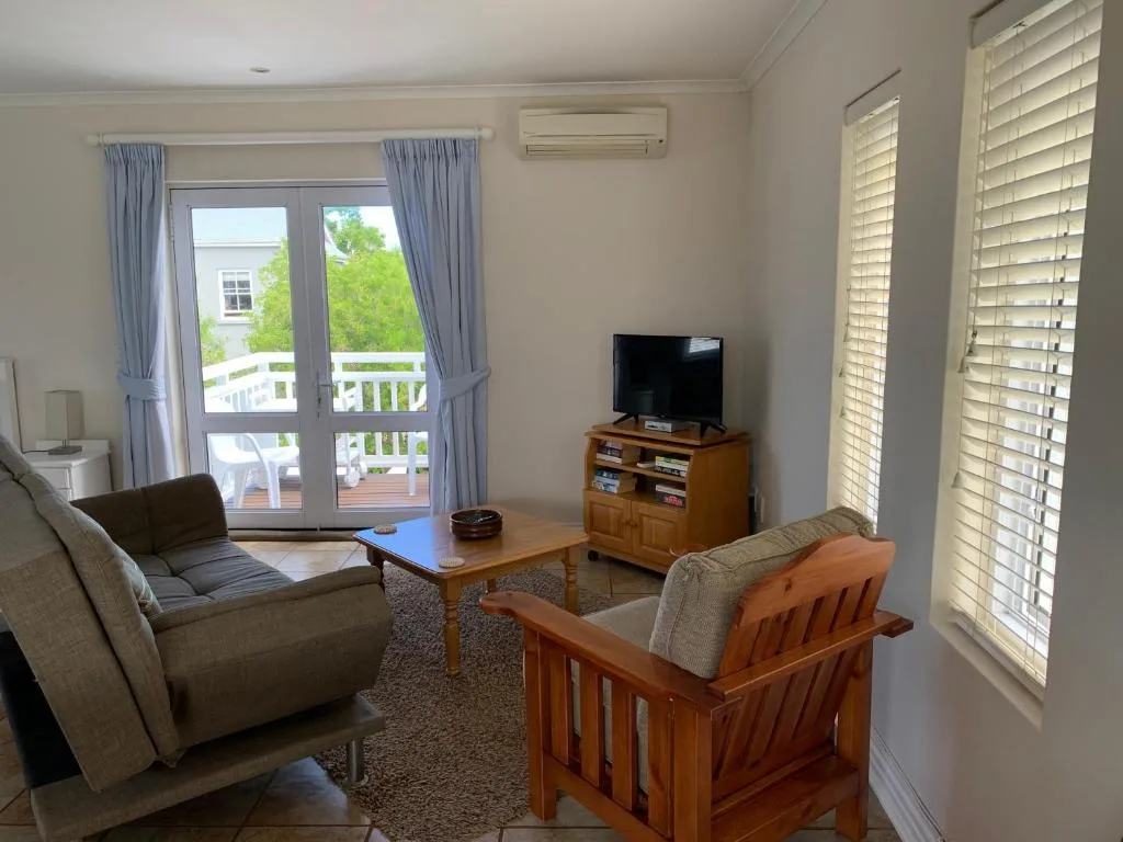 Bright living room with comfortable seating, TV, and deck access overlooking greenery