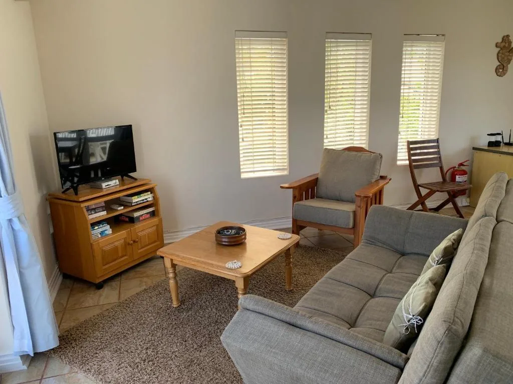 Bright lounge with grey sofa, wooden furniture, and TV entertainment setup