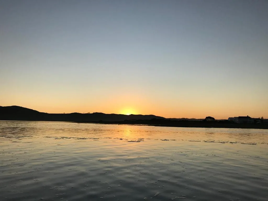 Sunset over Knysna Lagoon with mountains silhouetted against golden sky