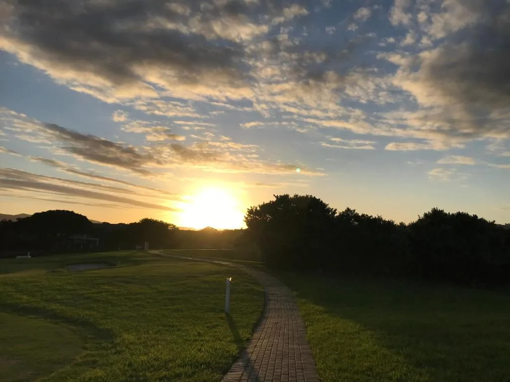 Golden sunset over manicured gardens and tree-lined landscape