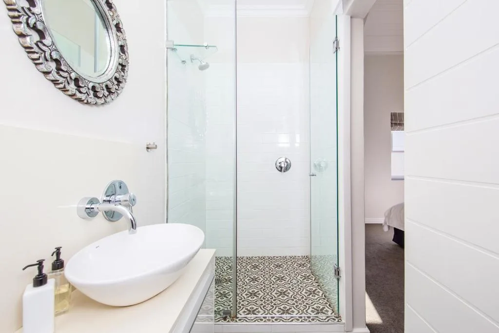 Modern bathroom with oval basin, glass shower enclosure, ornate mirror