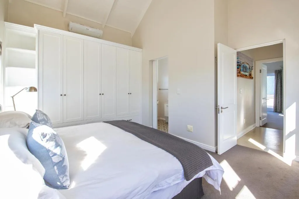 Bright bedroom with queen bed, white built-in wardrobes, and ensuite bathroom access