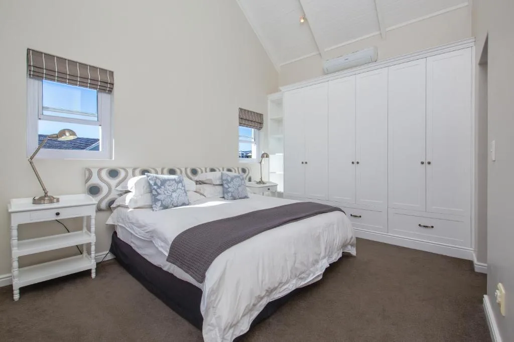 Bright bedroom with queen bed, white cabinetry, and coastal views through windows
