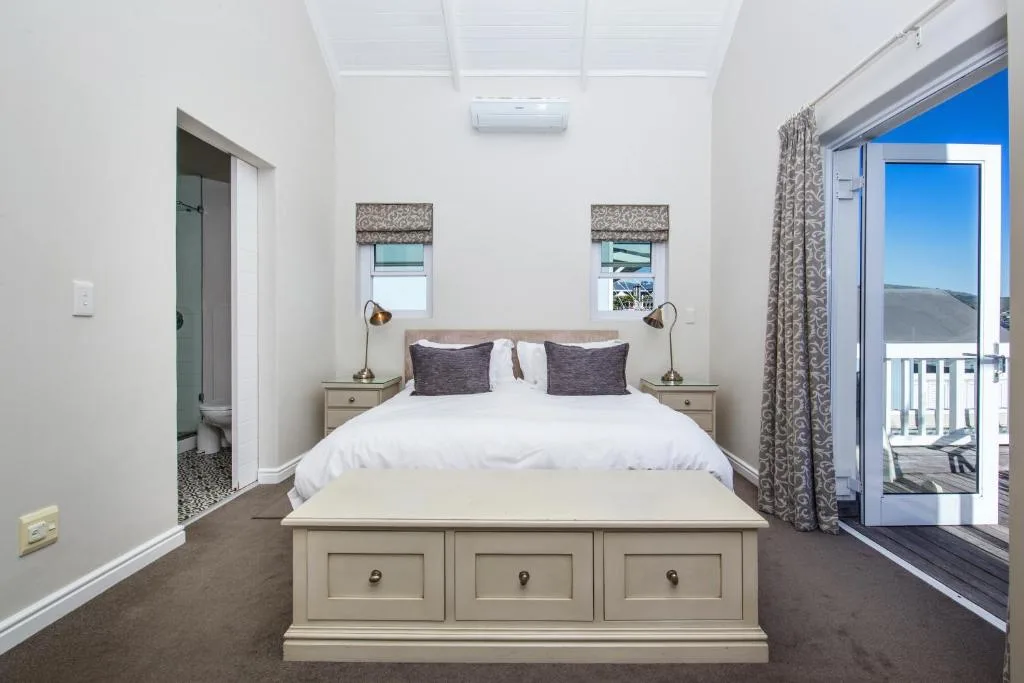 Bright bedroom with queen bed, white bedding, and sliding doors to deck