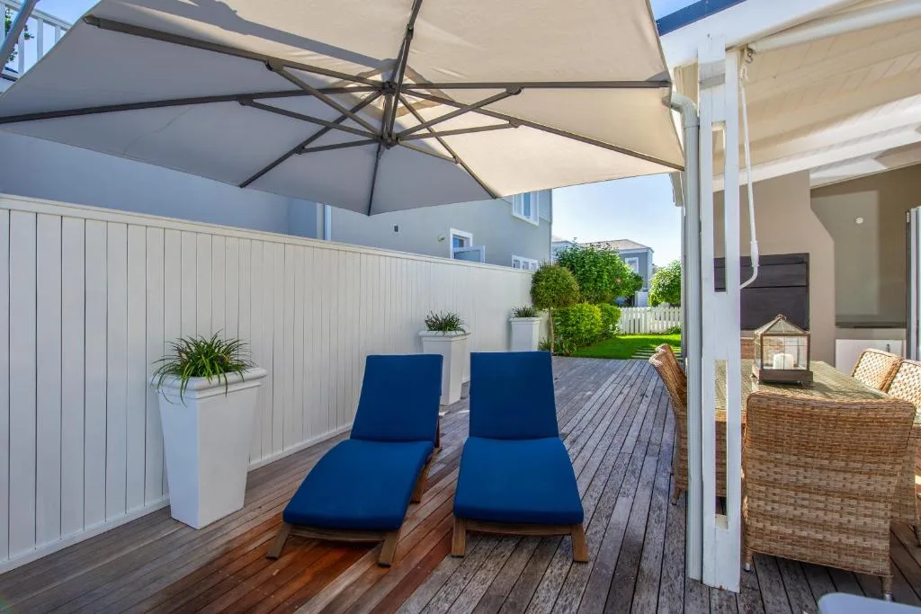 Shaded deck with loungers and potted plants overlooking garden