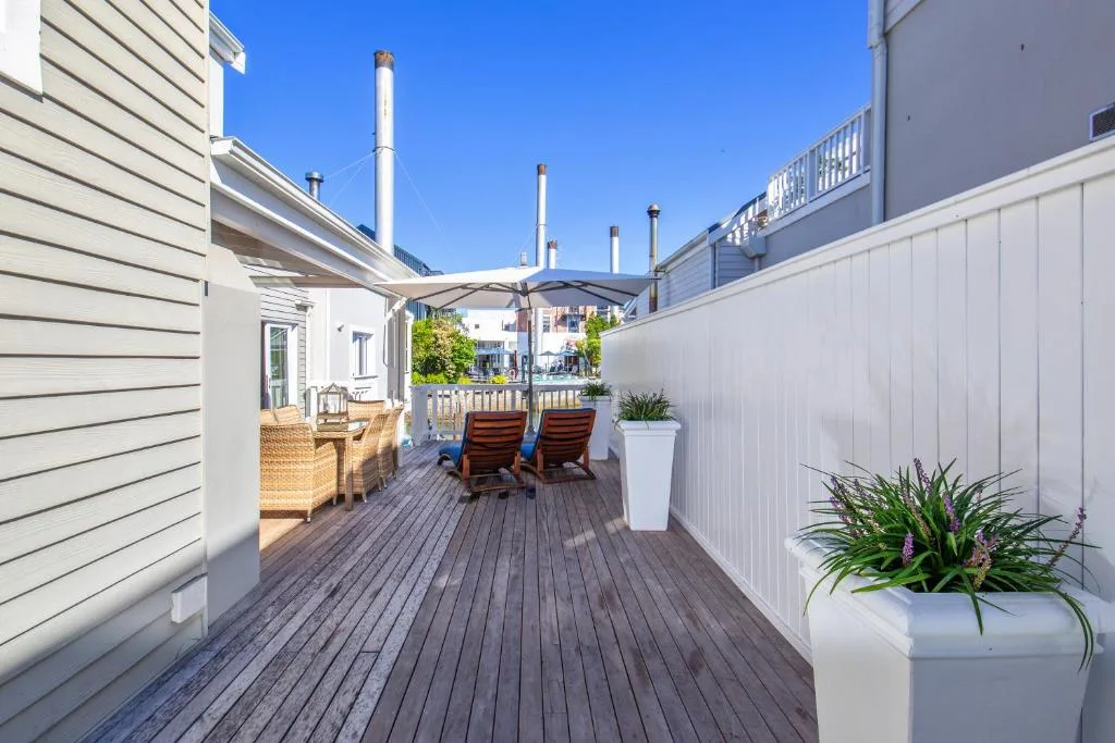 Spacious wooden deck with lounge chairs, potted plants, and coastal architecture views