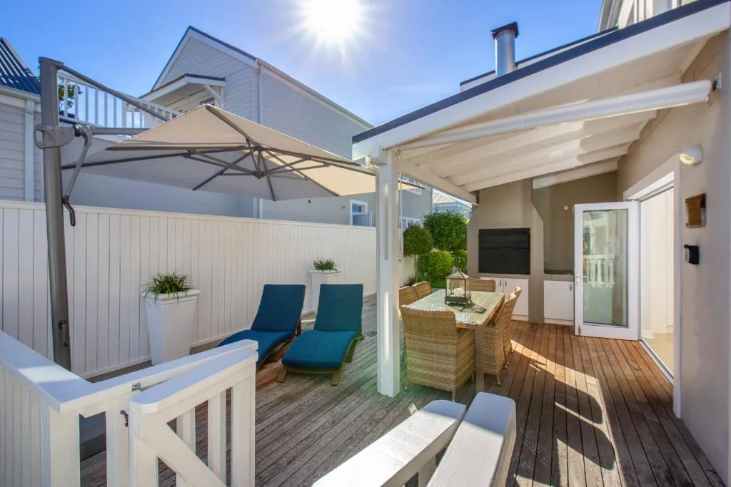 Covered outdoor deck with dining table, loungers, and umbrellas