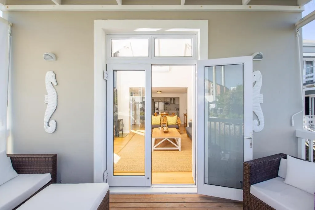 Covered deck with wicker seating overlooking open-plan lounge interior
