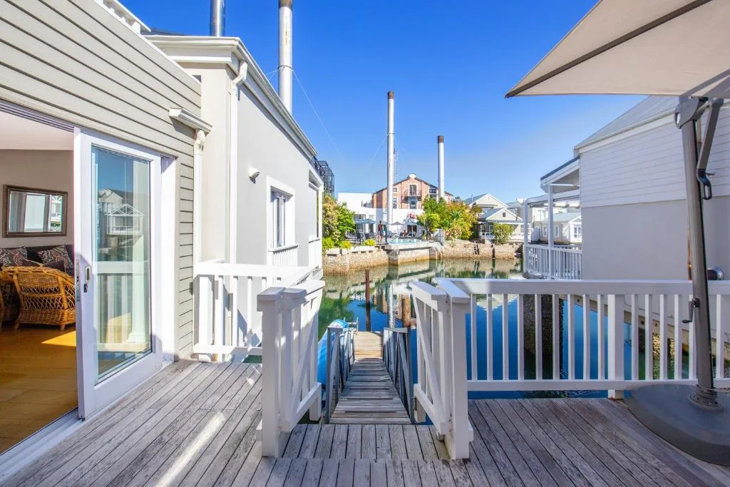 Waterfront wooden deck with white railings overlooking canal and boats