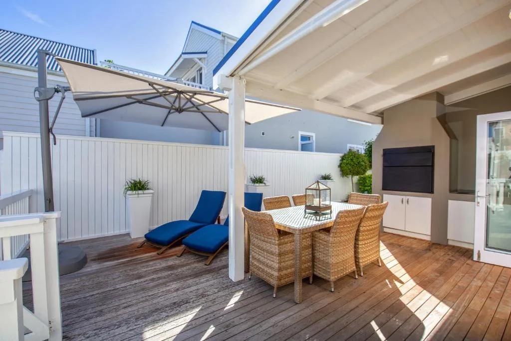 Outdoor deck with wicker dining set, loungers, and pergola shade