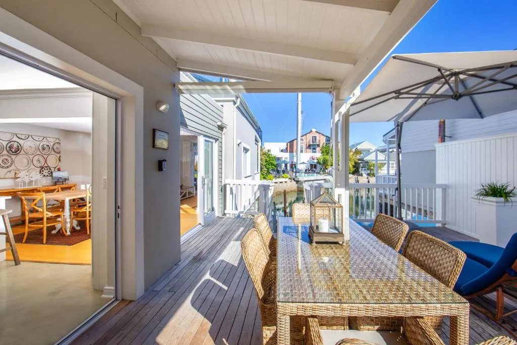 Covered deck with dining table, umbrellas, and coastal town views beyond