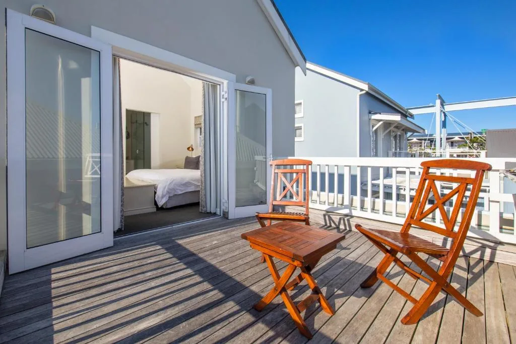 Wooden deck with orange chairs overlooking bedroom with ocean views