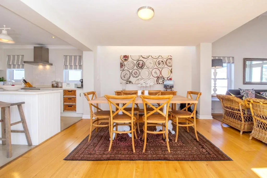 Open-plan dining area with wooden table, six chairs, decorative plates on wall