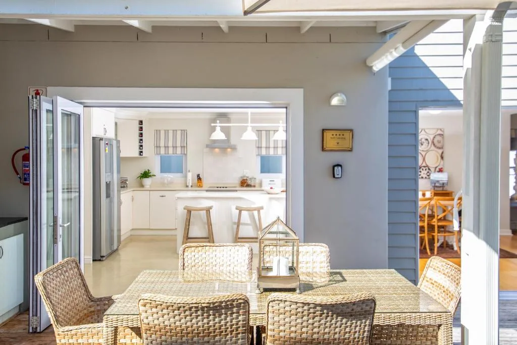 Bright dining area with woven chairs and open kitchen view beyond