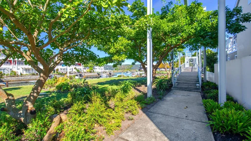 Lush garden pathway with mature trees leading to waterfront property