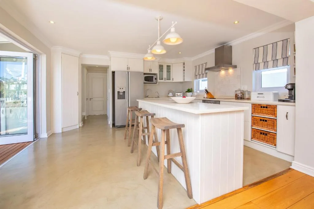 Modern open-plan kitchen with white cabinetry, island seating, and stainless steel appliances