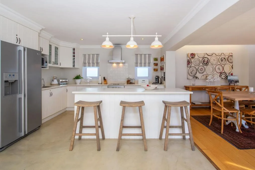 Modern open-plan kitchen with white cabinetry, island seating, and stainless steel appliances