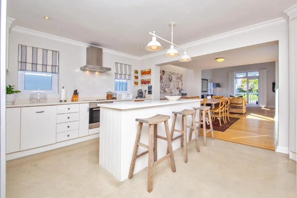 Modern white kitchen with island seating and open-plan dining area