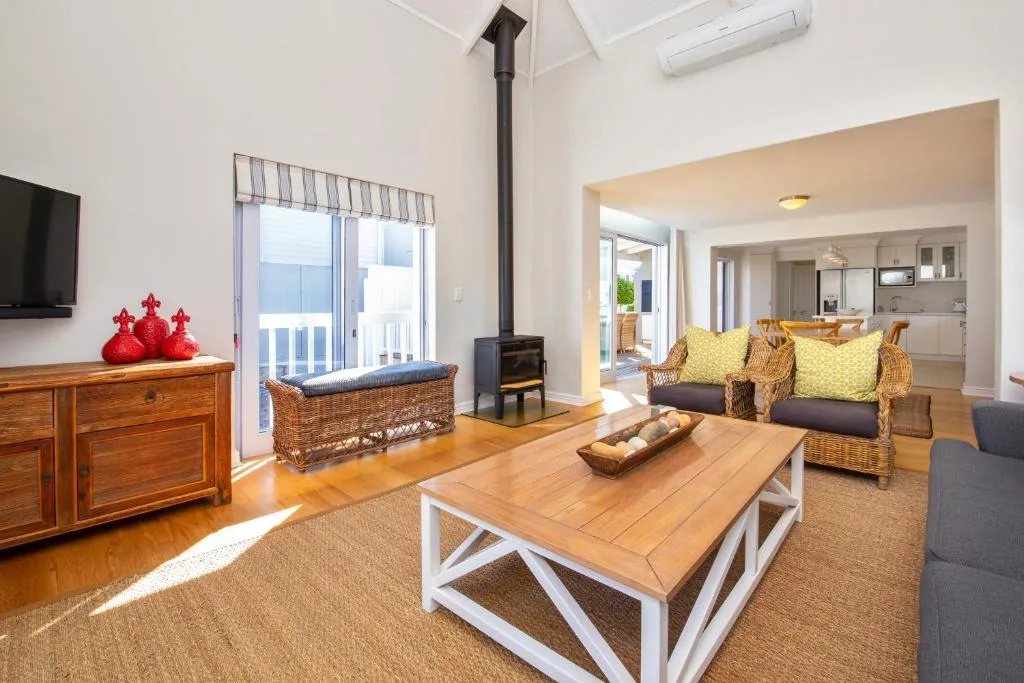 Spacious lounge with wood coffee table, wicker furniture, ocean views through glass doors