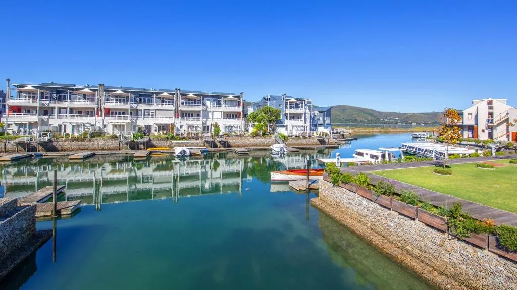 Waterfront buildings reflected in calm blue lagoon waters with boats