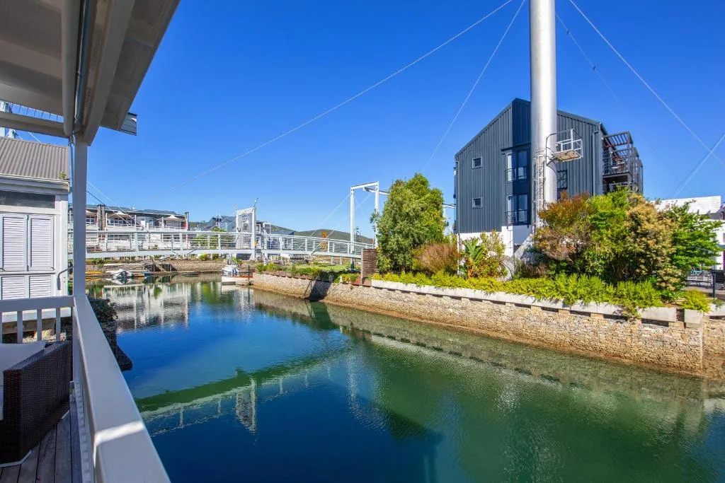 Scenic waterfront view of Knysna lagoon with modern buildings and clear blue sky